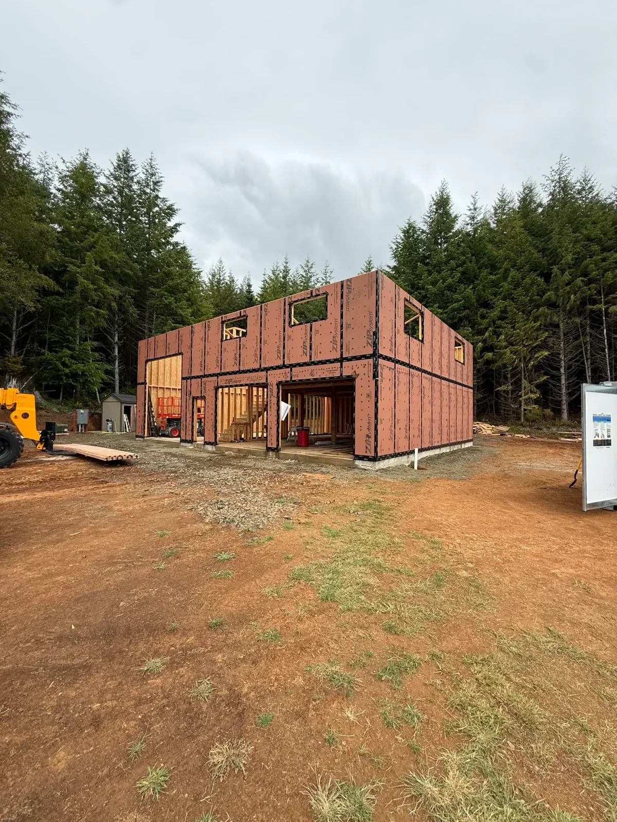 Two-story wood-framed house with ZIP System sheathing, framed window openings, and exposed framing at the entry