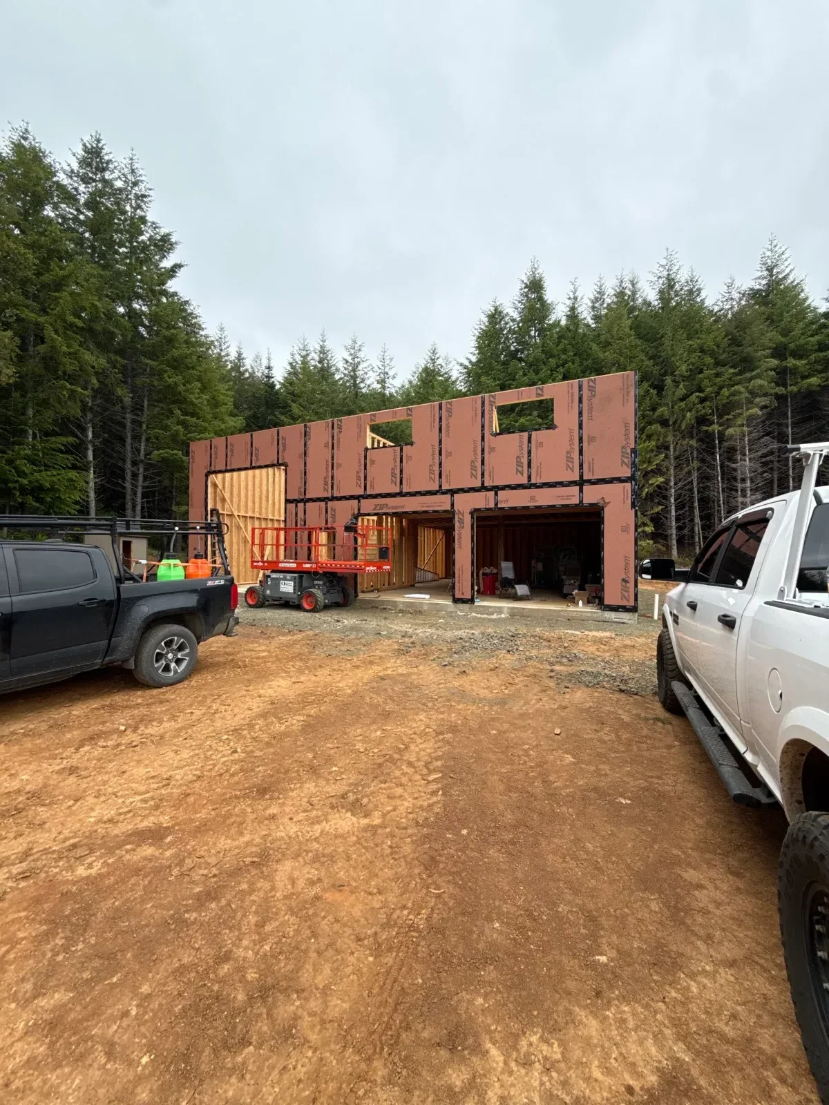 New home framing with orange ZIP System sheathing, cut window and door openings, and exposed lumber framing inside