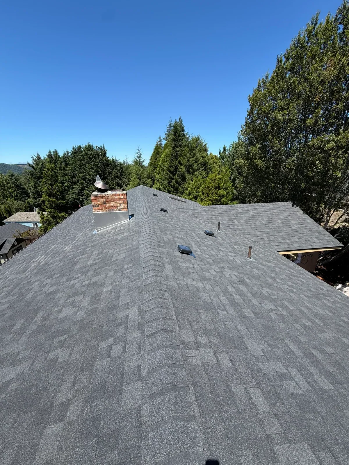 Gray architectural asphalt shingle roof with dimensional blend, roof vents, skylight, and terra cotta tile accent
